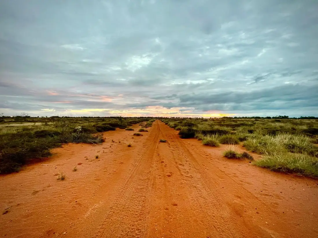 Red dirt road through dry scrub at sunset