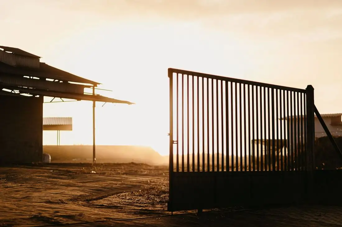 Shed roof and steel gate silhouetted at sunset