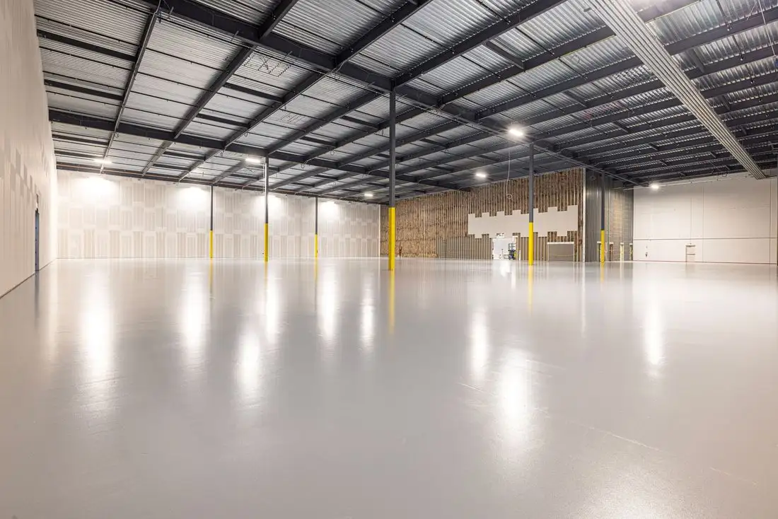 Empty steel-framed building with a large finished concrete floor